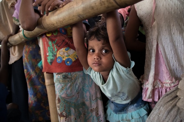 Bambina Rohingya mezzo busto guarda in camera. Immagine molto colorata.