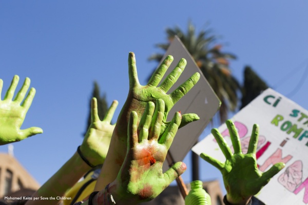 mani colorate di verde che si alzano verso il cielo durante una manifestazione per l'ambiente