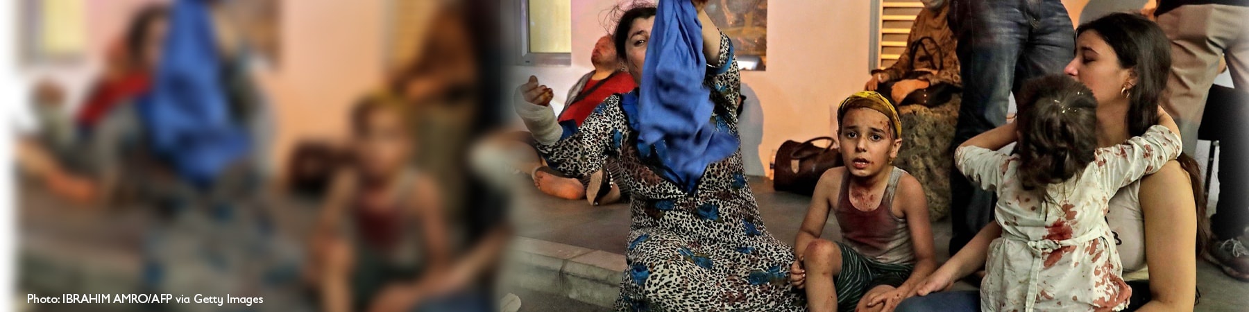 persone sedute a terra ferite tra cui due bambini feriti e una donna velata di blu con un braccio fasciato Libano