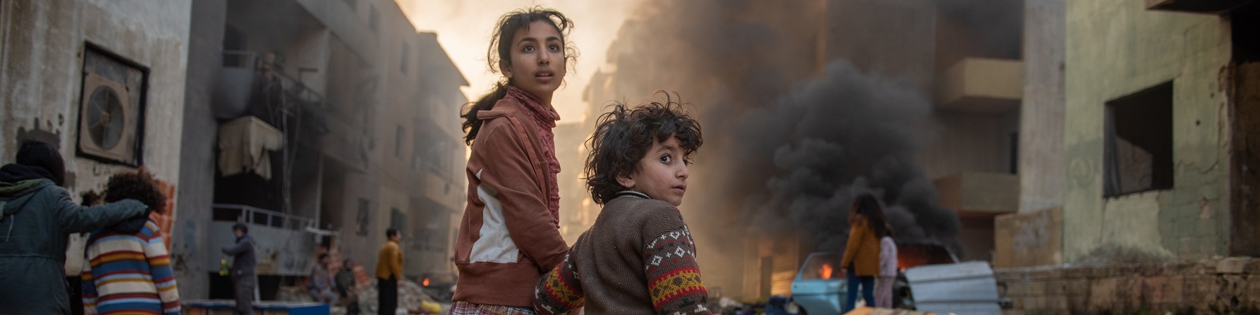 bambina e bambino mano nella mano in contesto di guerra