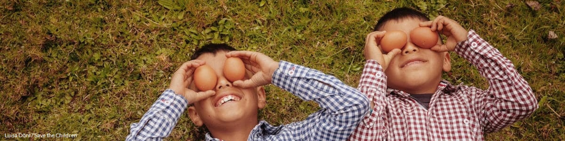bambini sorridenti su un prato con uova di gallina sopra gli occhi 