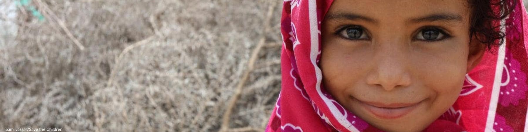 bambina in yemen sorridente con velo fucsia in testa