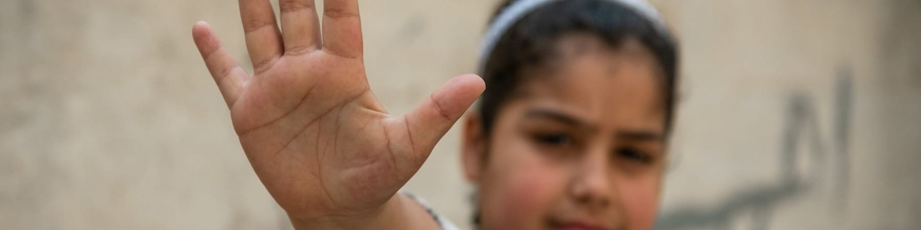 Primo piano di una bambina con la mano davanti facendo gesto di stop