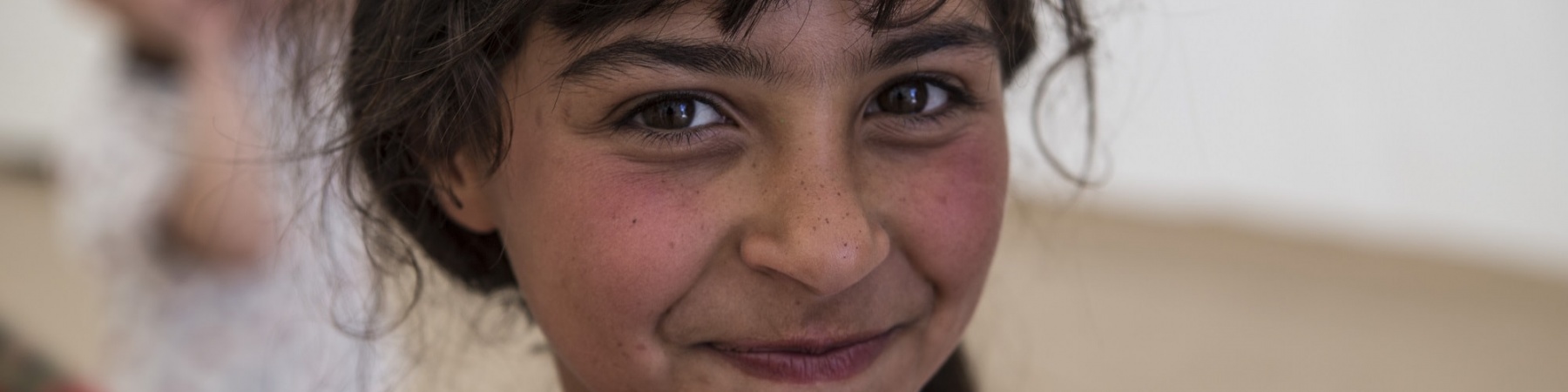 primo piano bambina mora e sorridente con maglietta rosa