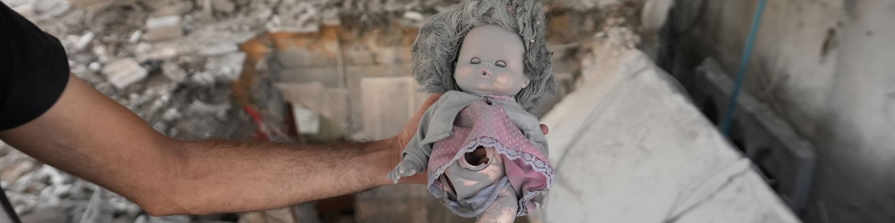 peluche di una bambola sopra le macerie a Gaza senza un arto