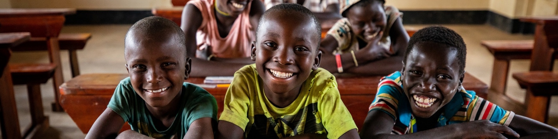 una classe di bambini seduta ai banchi di scuola in Africa, Uganda