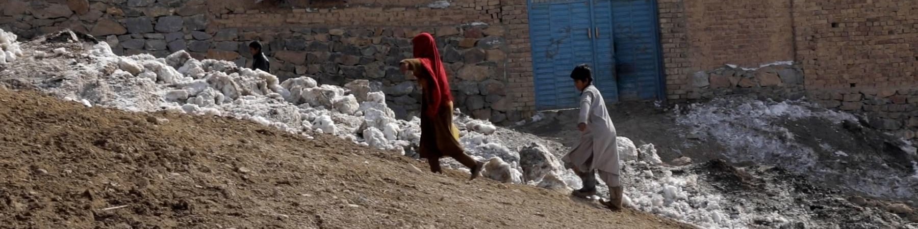 Due bambini afghani camminano in salita all interno del loro villaggio