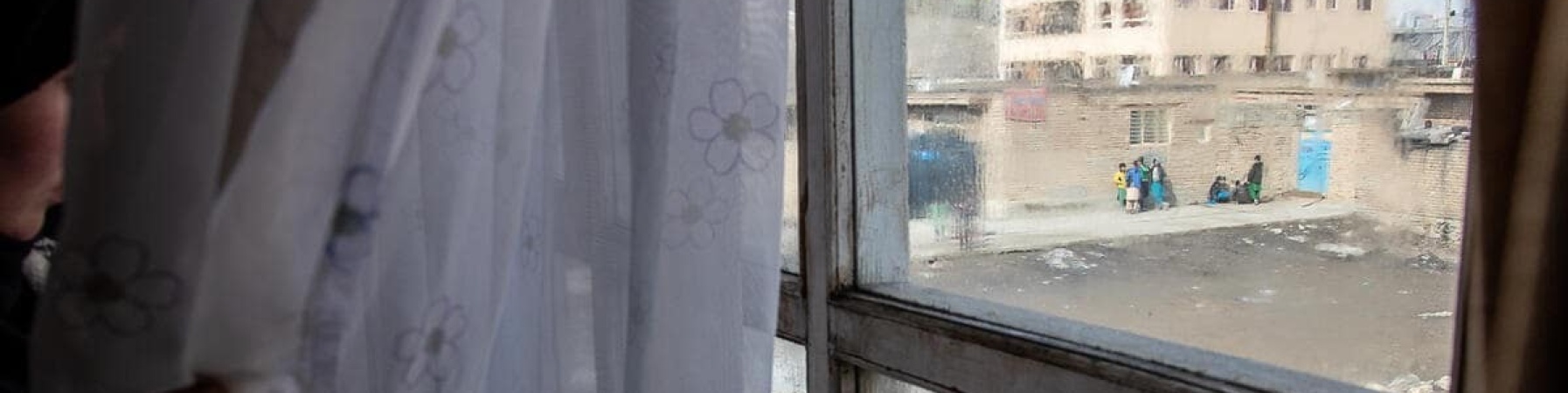 donna afghana ch guarda al di fuori della finestra 
