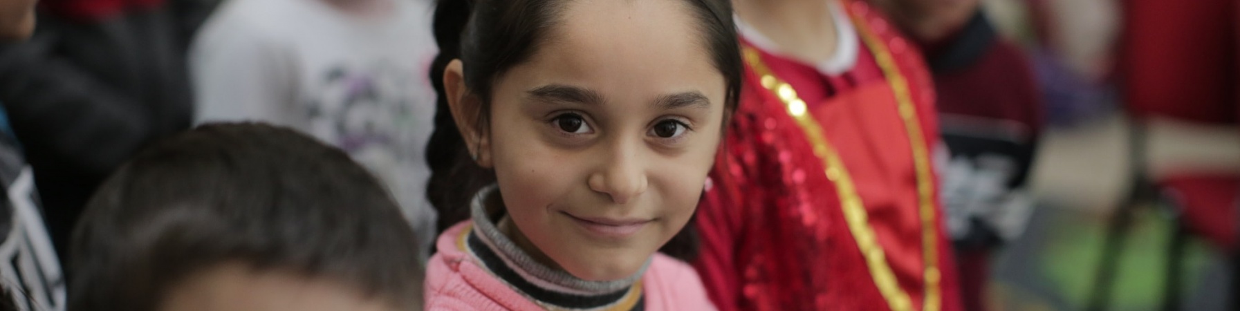 4 bambini albanesi guardano in camera e sono vestiti in modo tradizionale e molto colorato