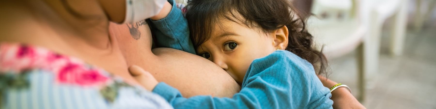 Una mamma ripresa lateralmente mentre allatta il proprio bambino