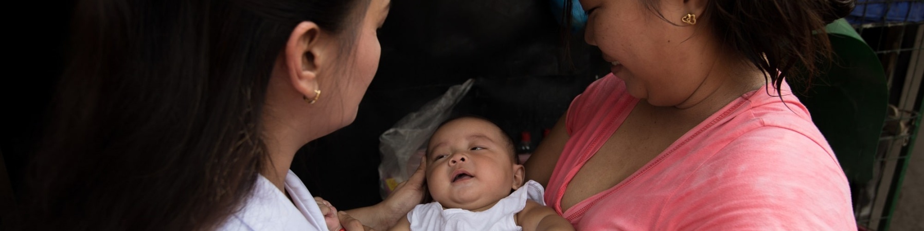 mamma con in braccio la sua bimba neonata insieme a un operatrice di Save the Children
