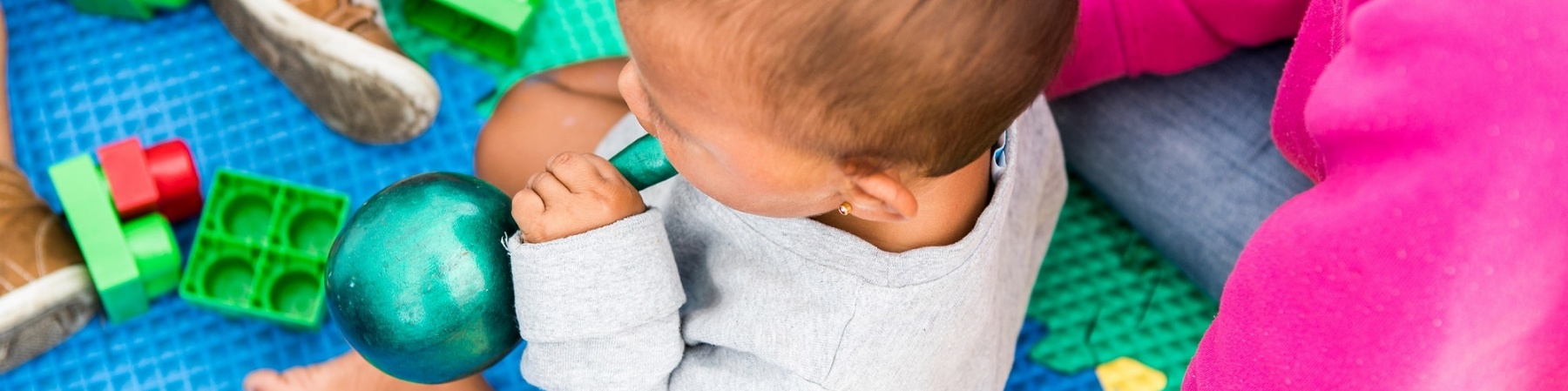 bimbo seduto su un tappeto colorato di gomma che gioca insieme alla sua mamma