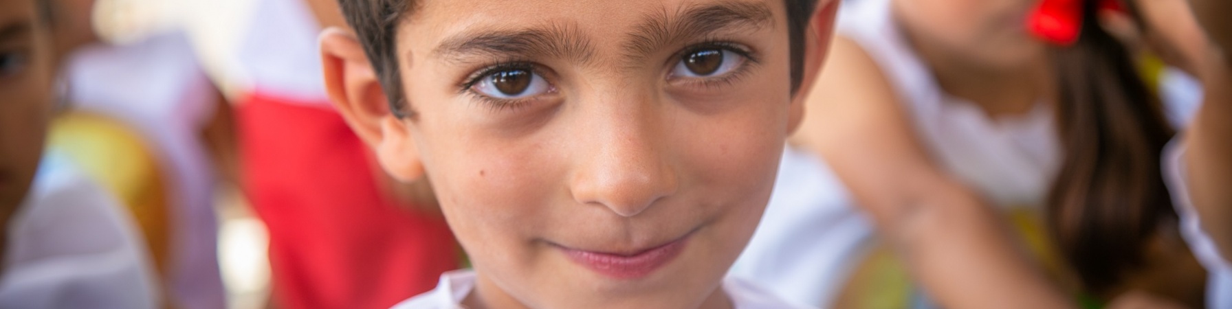 Primo piano di un bambino che guarda in camera con camicia bianca