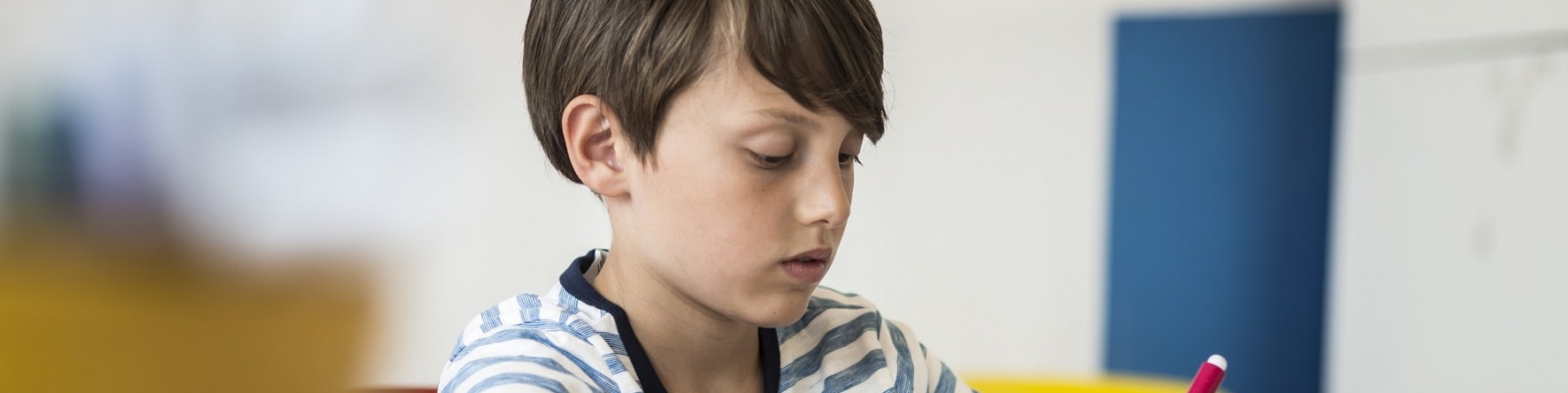 bambino seduto a un banco di scuola mentre fa i compiti