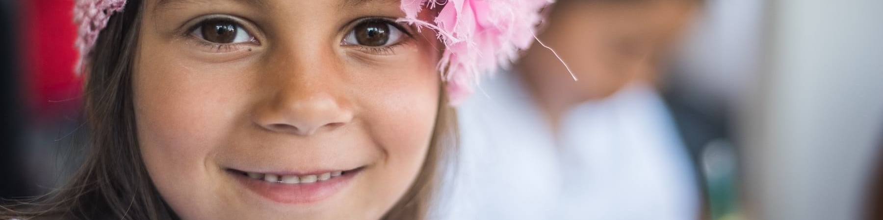 Primo piano bambina sorridente con fascia rosa in testa