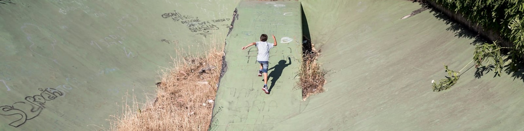 Un bambino di spalle corre in uno degli spazi abbandonati di Ponte di Nona a Roma