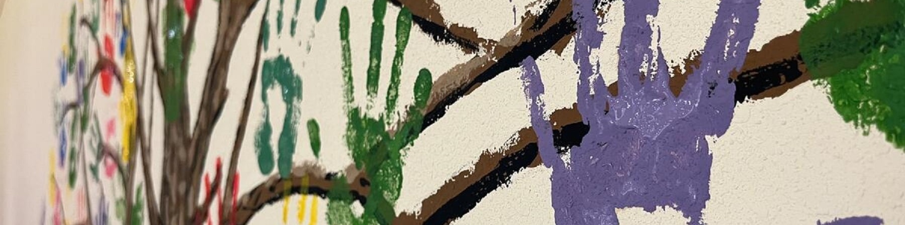 impronte mani colorate di bambini dipinte su muro attorno a rami 