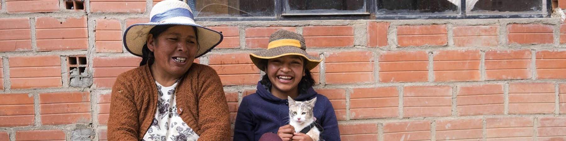 Donna e bambina in Bolivia sedute per terra, sorridenti