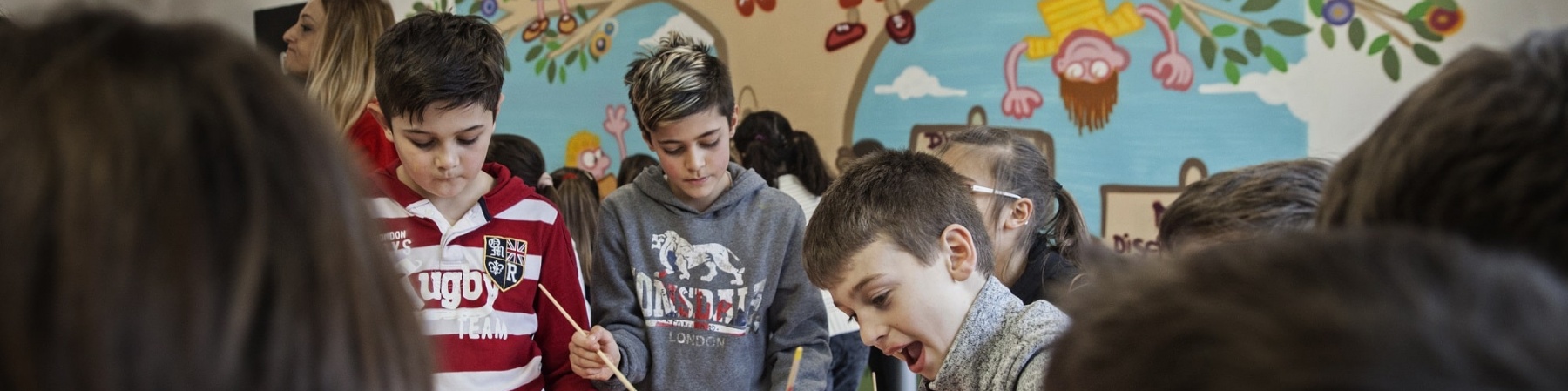bambini a un tavolo a scuola mentre disegnano insieme con dei pennelli