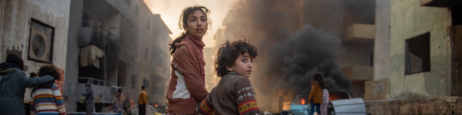 bambina e bambino mano nella mano in contesto di guerra