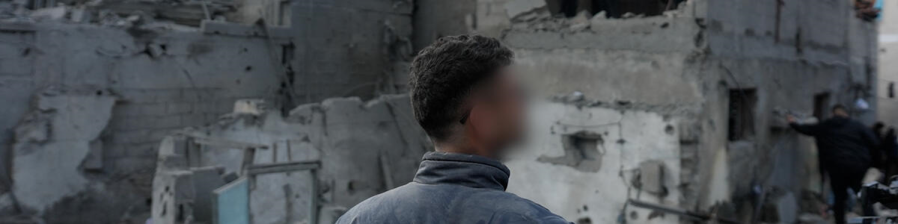 uomo di spalle di fronte ad un palazzo distrutto a Gaza