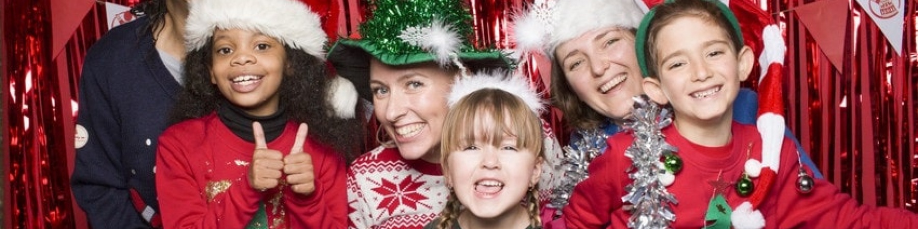 tre bambini e tre adulti vestiti con maglioni natalizi per il christmas jumper day