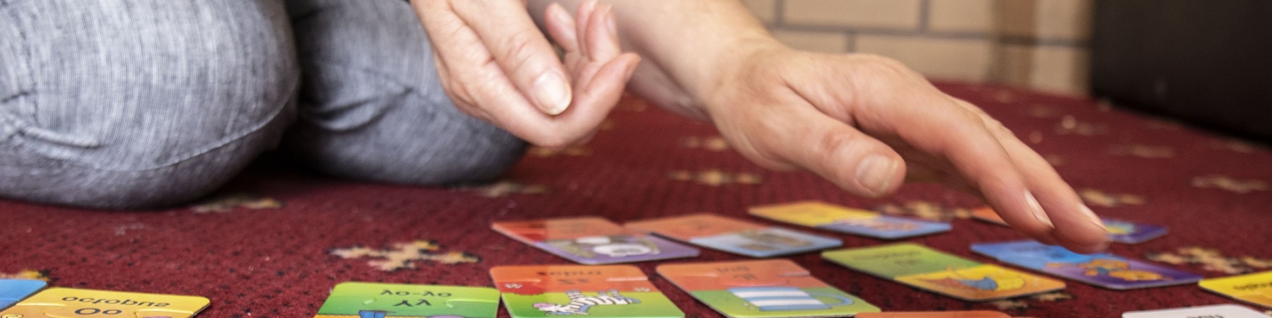primo piano di card colorate appoggiate a terra e mani di un adulto che le tocca