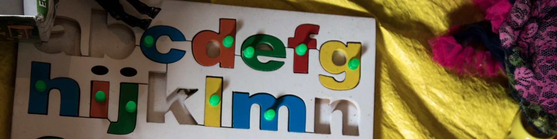 tabellone per bambini con lettere dell'alfabeto colorate estraibili poggiato su un lenzuolo giallo