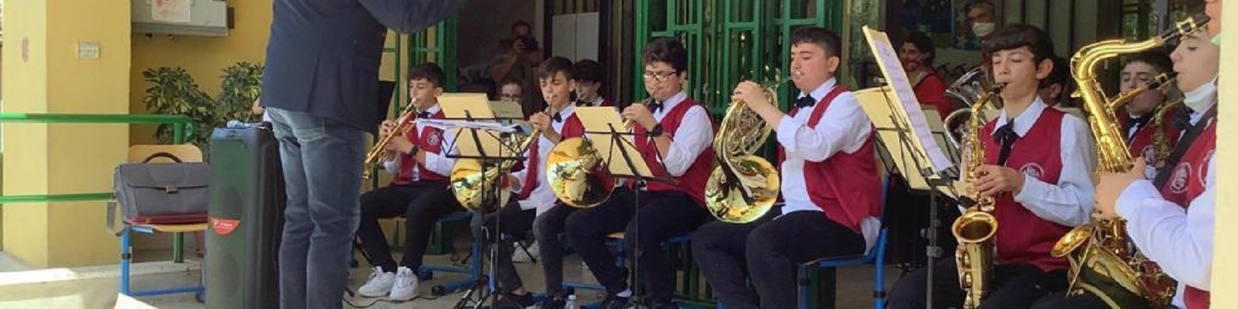 Insegnante che dirige l'orchestra di studenti che suonano strumenti musicali come trombe e flauti