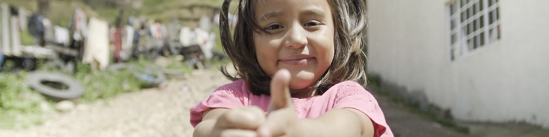 Una bambina messicana con codini e maglietta rosa mostra come ha imparato a lavarsi le mani.