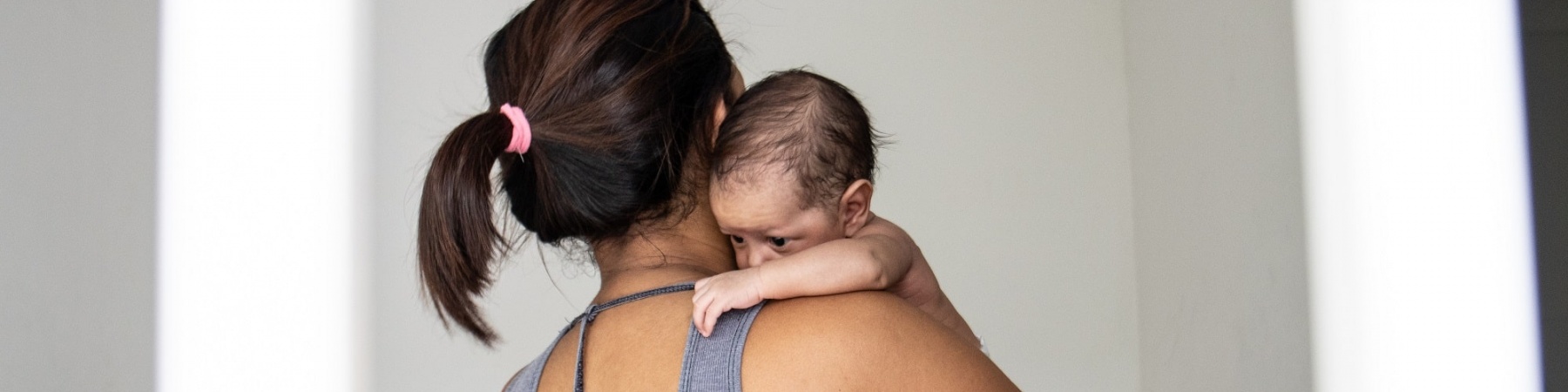 mamma con bambino neonato in braccio di spalle