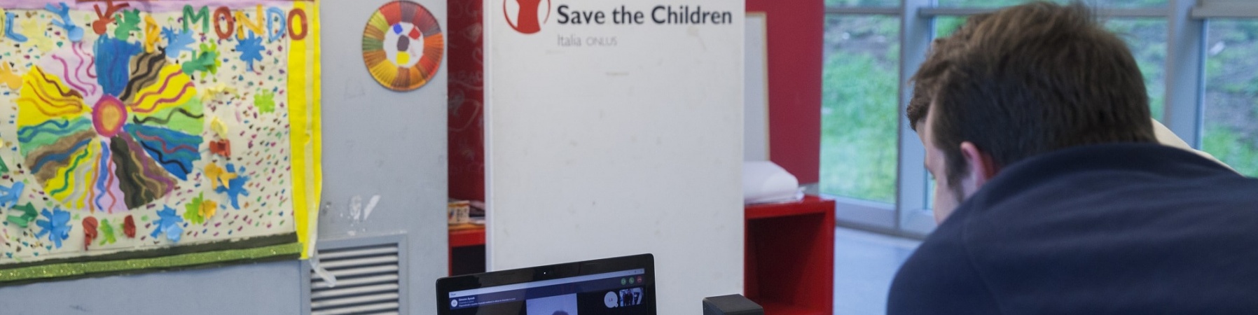 operatore di save the children italia davanti al pc in collegamento con un ragazzo