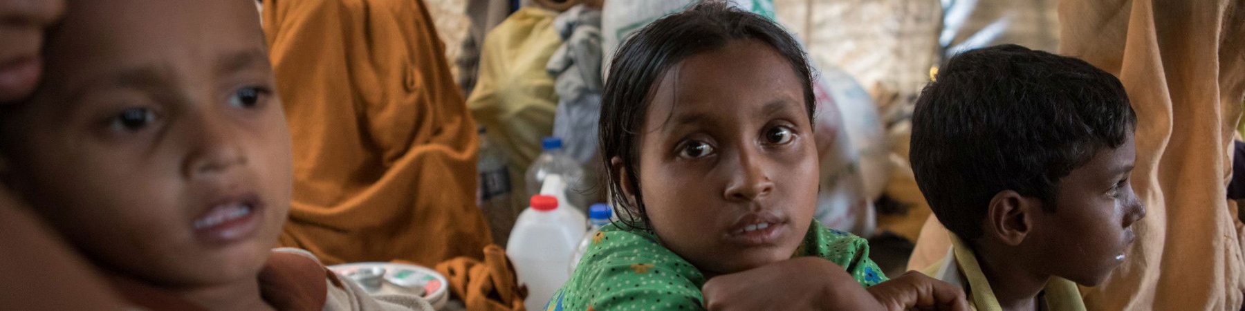 Una bambina e due bambini rohingya seduti vicini