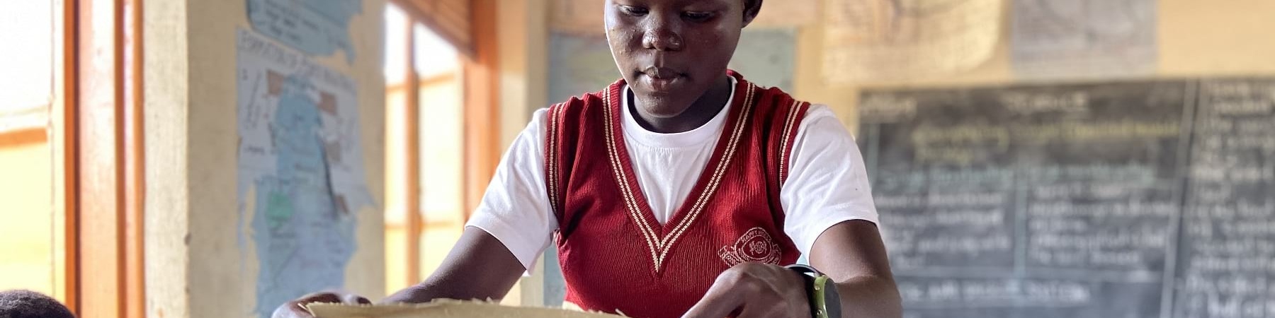 Ragazza ugandese in divisa scolastica tiene in mano slip autoprodotti.