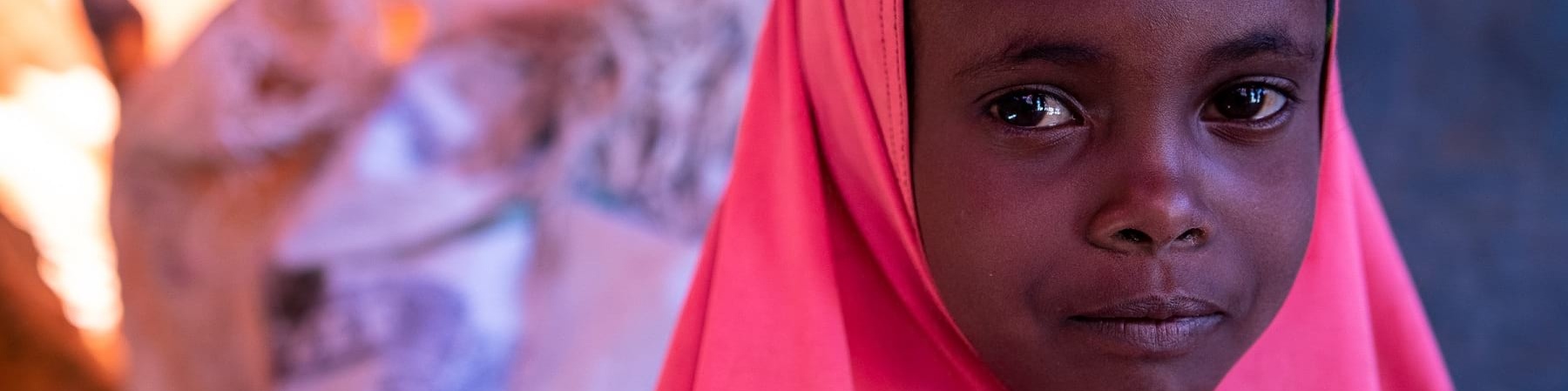 Primo piano di una bambina sola con un chador rosa fucsia