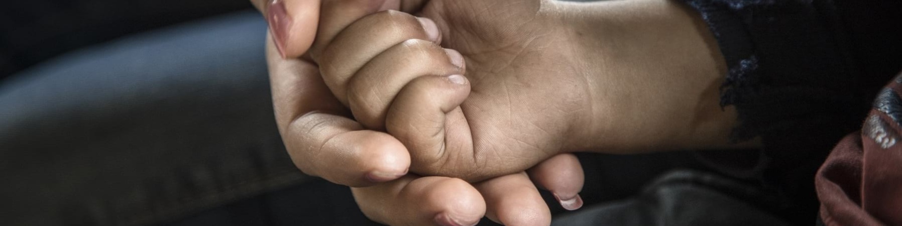 Primo piano di mano di donna che tiene nella sua la mano di un bambino piccolo