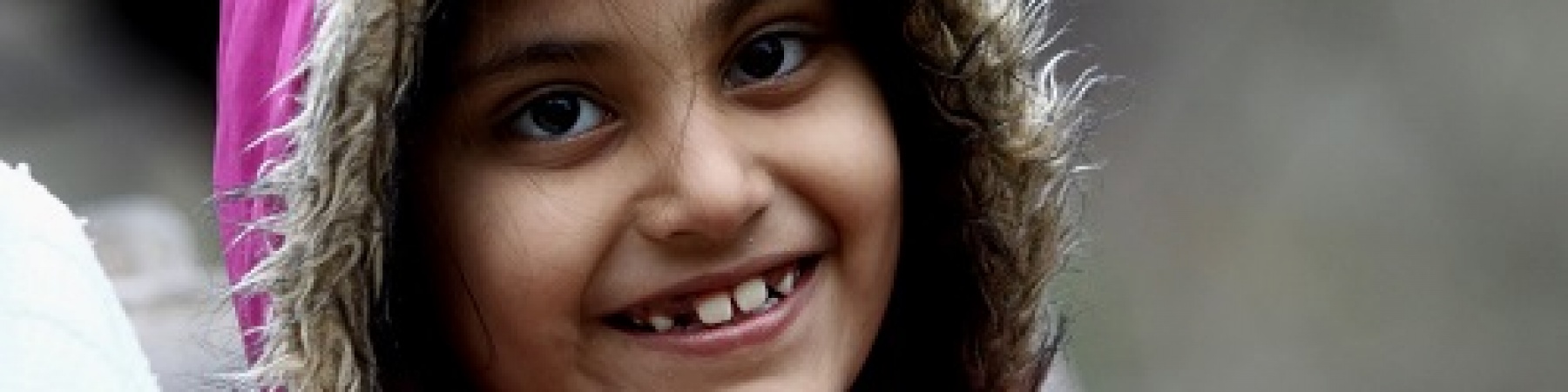 Emergenza freddo bambina con cappotto rosa e cappuccio che ride