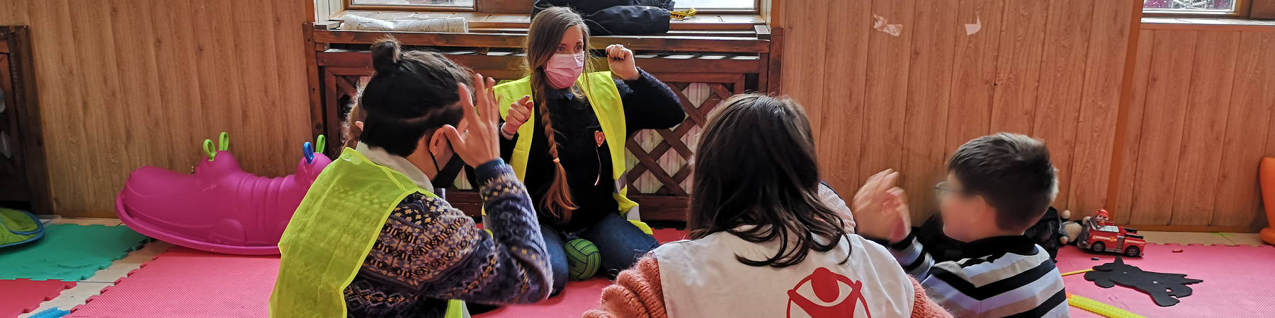 operatori save the children giocano a terra insieme a un bambino su un pavimento colorato di rosa