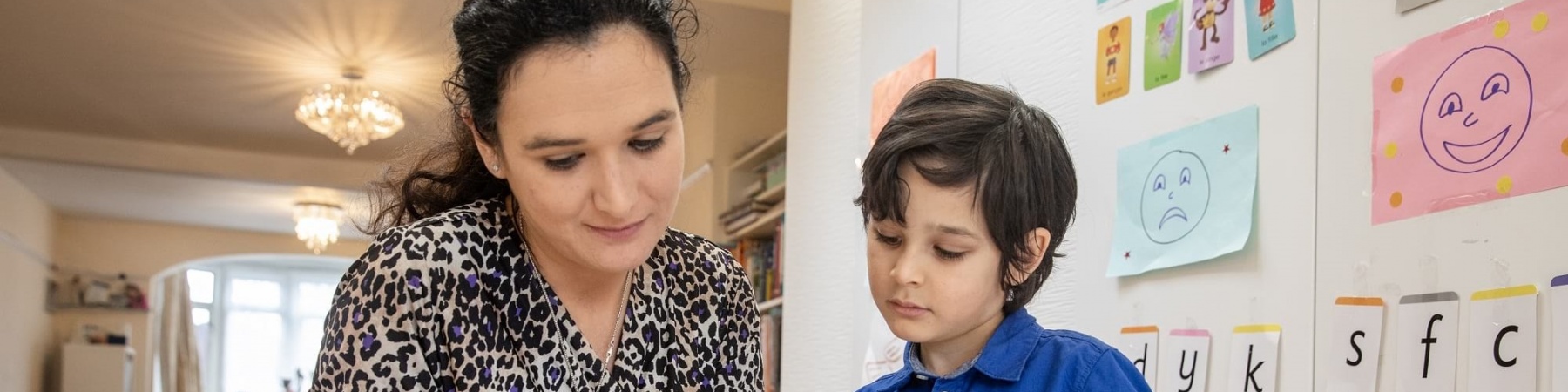 E sempre più difficile essere mamme in italia mamma e figlio sfogliano libro con sfondo di una casa e di una libreria con disegni fatti dal bambino