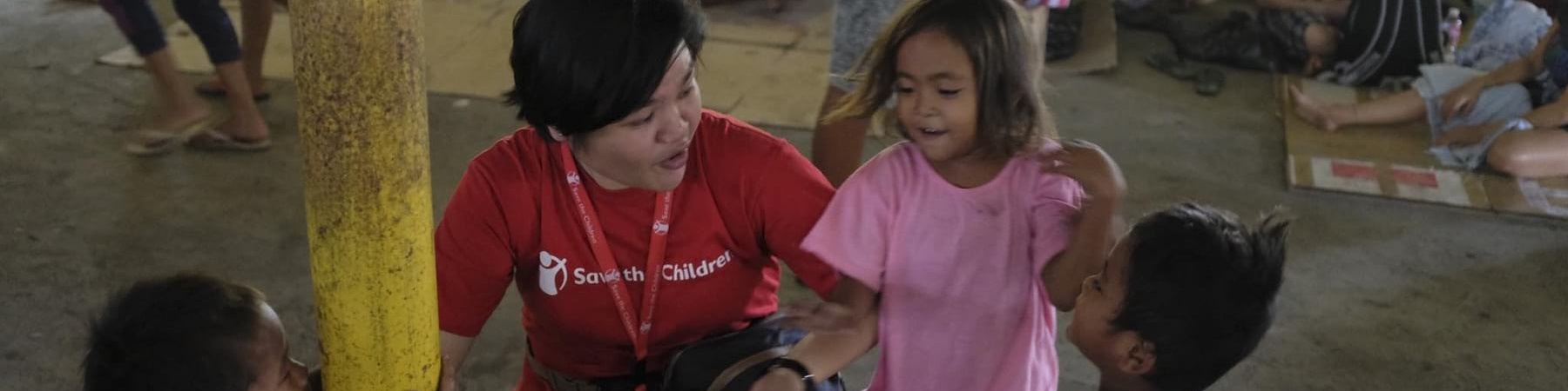 Operatrice save the children parla con bambini in spazio a misura di bambino allestito nelle Filippine per emergenza eruzioni vulcano Taal