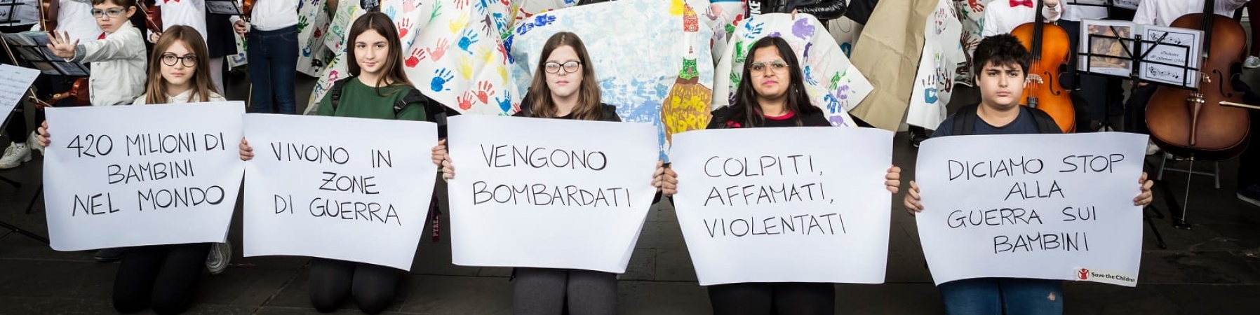 Bambini tengono in mano cartelli per flash mob alla Stazione Roma Termini