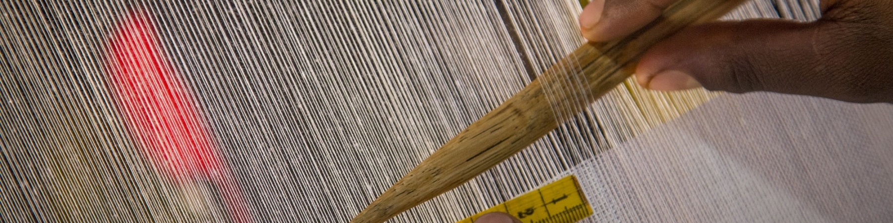 dettaglio di mani che creano un vestito su un telaio