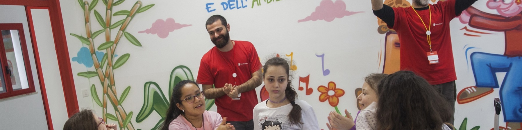 Bambini e operatori Save the Children intorno a un tavolo