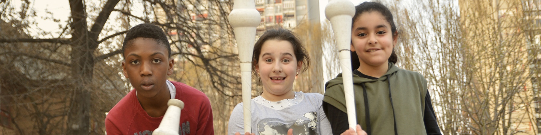 foto all aperto di 3 bambini con birilli in mano che giocano