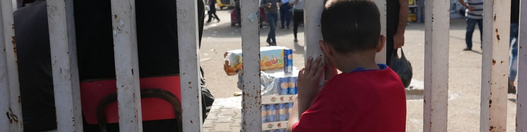 Bambino a Gaza che guarda oltre delle sbarre