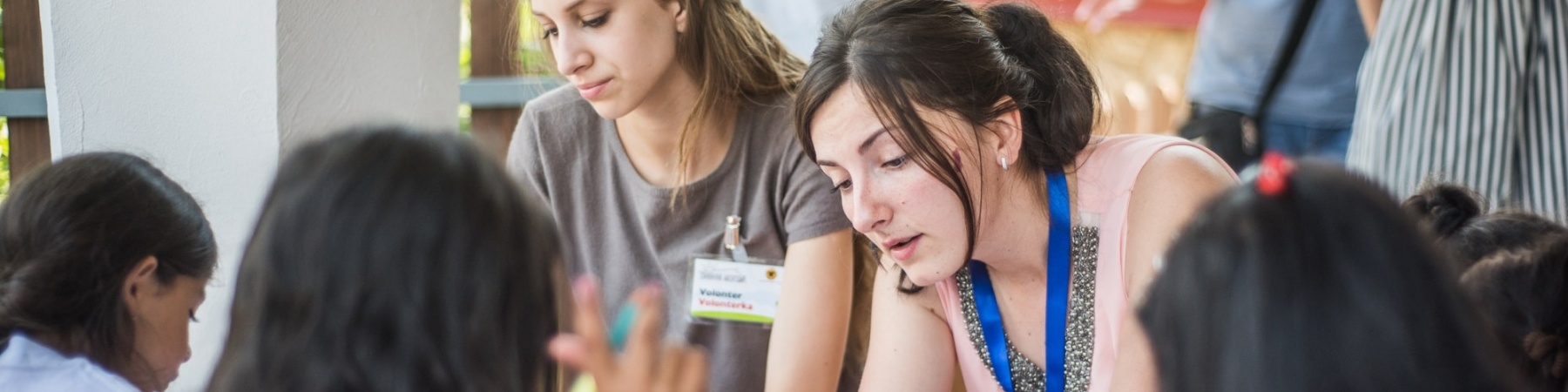 due educatrici e tre studenti sono seduti a un banco di scuola a fare attività educative insieme