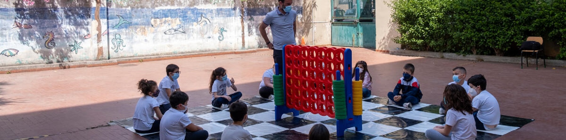 Bambini seduti a terra che ascoltano il maestro