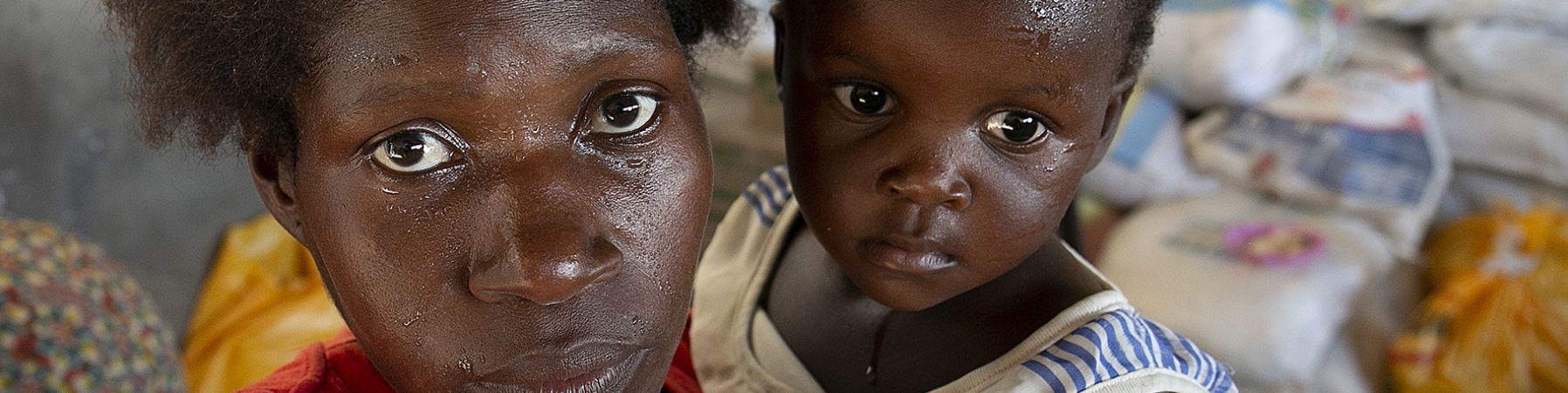 Primo piano di mamma e figlio di origine mozambicana. Il bambino è in braccio alla donna.