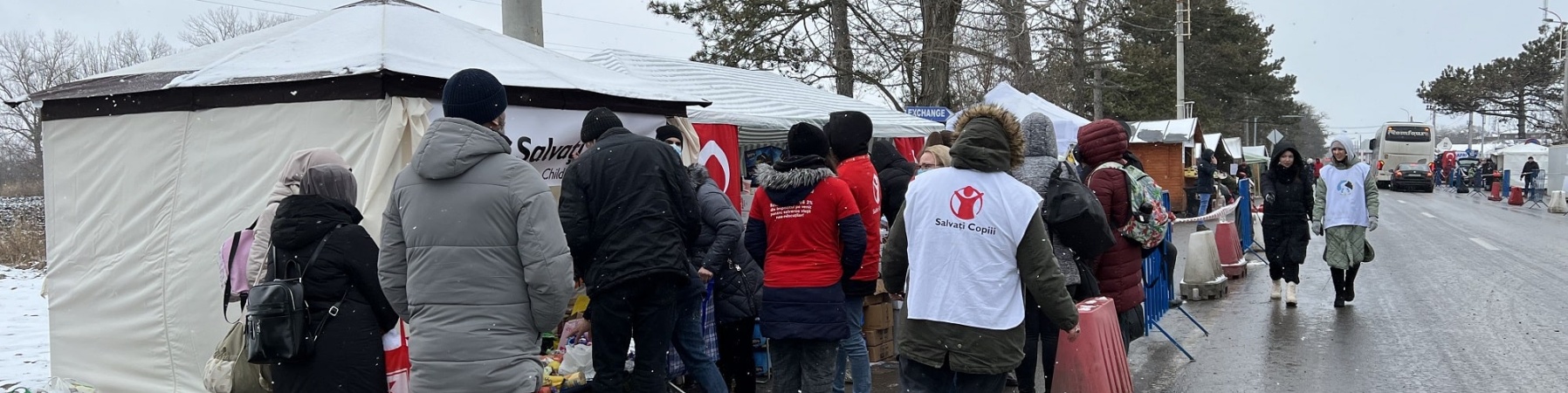 strada, neve, persone che si avvicinano a uno stand di save the children per ricevere degli aiuti