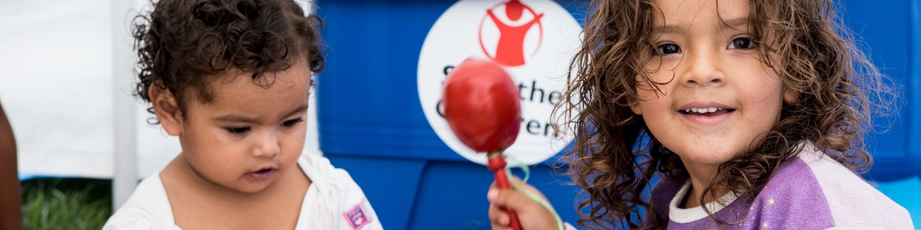 due bimbe piccole sedute per terra su un tappetino giocano con degli strumenti musicali per bimbi